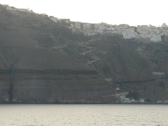 09Aug20 Santorini 03 entering harbor - volcanic caldera town built on rim of steep rock face.JPG